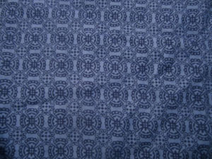 Cornflower blue cotton fabric with a darker blue circles, flower shapes, and four-pointed stars repeating tile pattern.