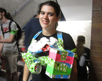 A user with a large duct tape pouch filled with socks attached to their chest. The custom harness also has a phone pocket, a water bottle pocket, a box, and a roll of duct tape attached. 