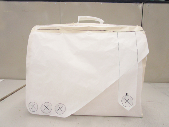 Full size version of bag made of pattern paper and tape. Button placement and seams are drawn onto sketch.