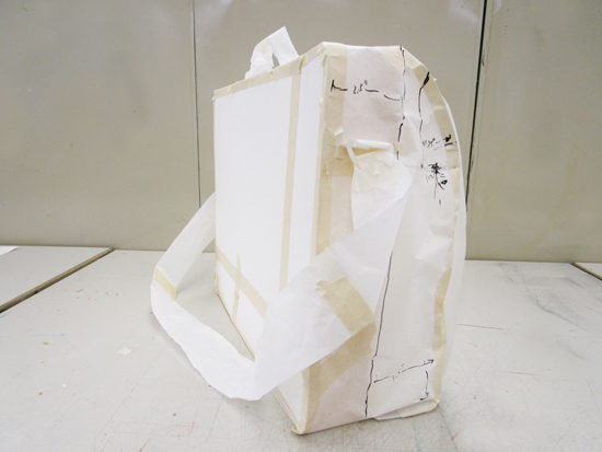 Full size version of bag made of pattern paper and tape. Measurements are written on bag.